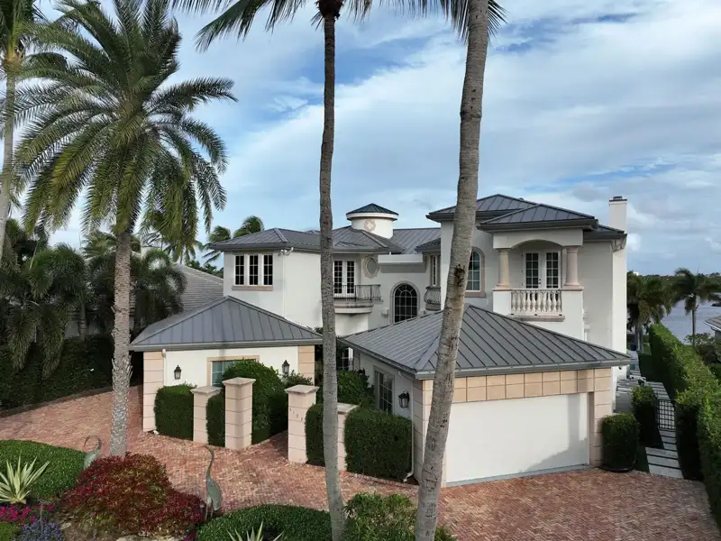 White stucco Jupiter home with a gray roof and palm trees