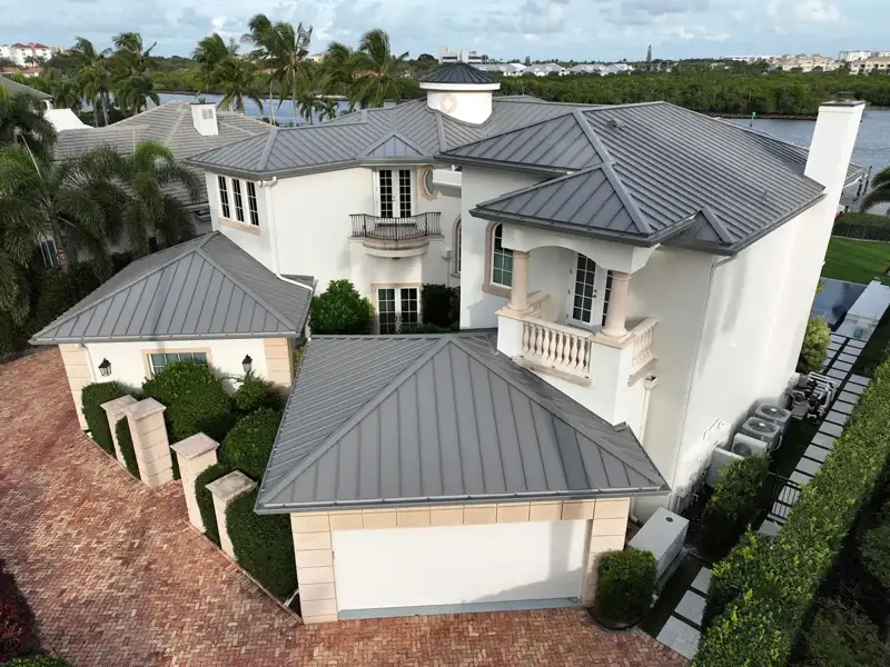 Large white home with a gray metal roof near the water