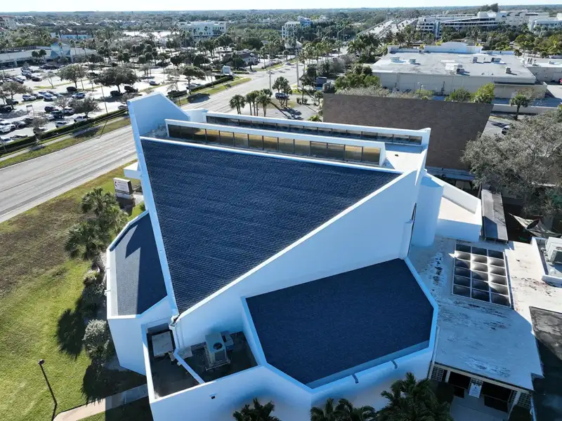 Aerial view of a white multi angled building with a blue roof